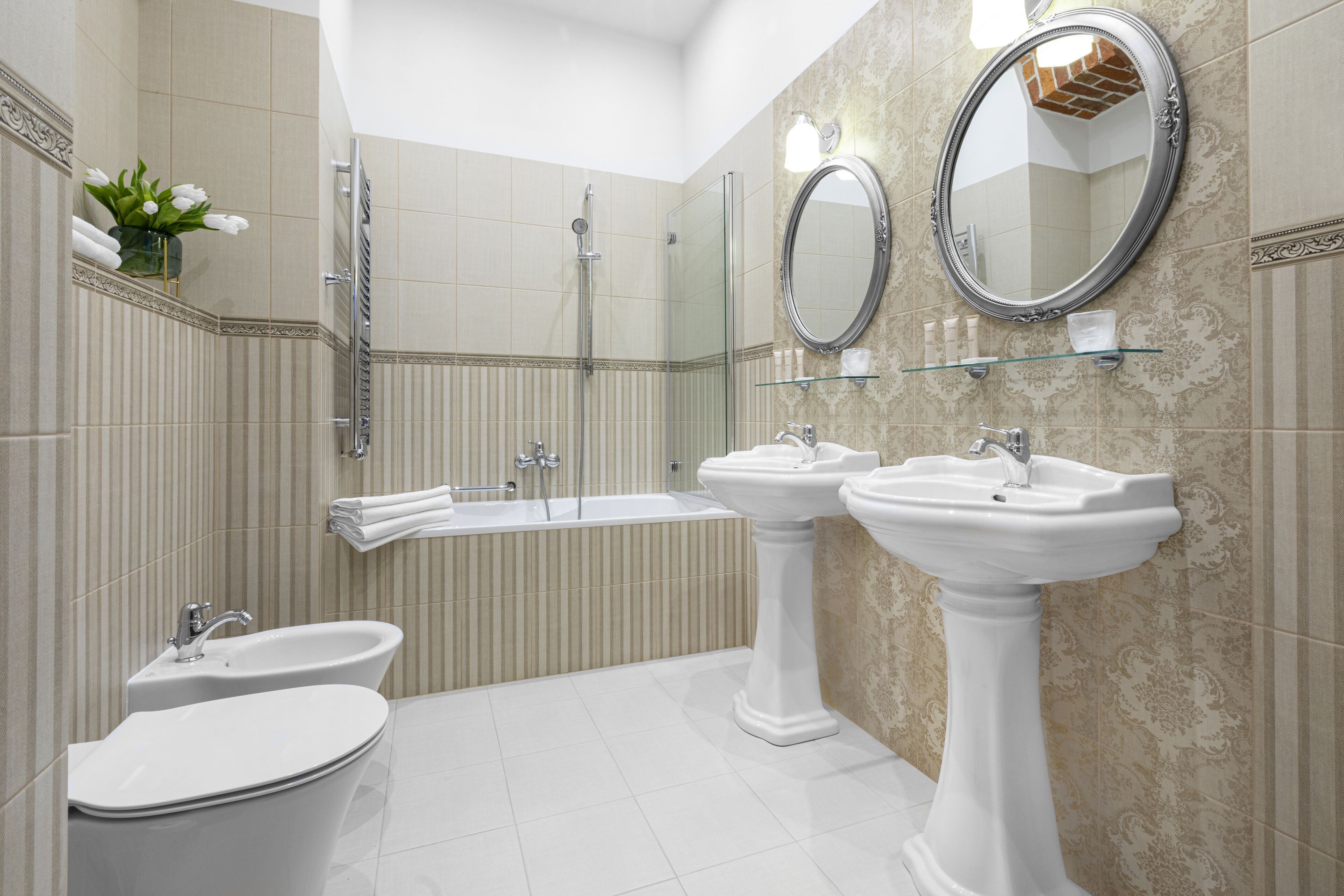 Une salle de bain moderne avec une baignoire, deux lavabos, une douche à l’italienne et des miroirs décoratifs.