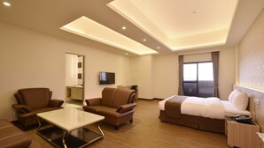 A modern hotel room with a large bed, two sofas, a small table, and a TV. - Midu Business Hotel (Xiluo)