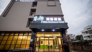 The exterior of Midu Business Hotel with a modern design, large windows, and a visible reception area. - Midu Business Hotel (Xiluo)