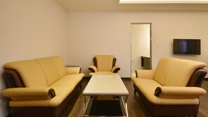 A room with two yellow sofas, a central table, and a flat-screen TV on the wall. - Midu Business Hotel (Xiluo)