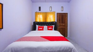A bedroom with a bed, a wooden door, and a yellow curtain. - OYO 1721 A. Yani 95 Residence (Banyuwangi)