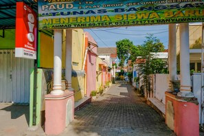 Una calle estrecha flanqueada por edificios de colores, incluyendo un letrero visible de un grupo de juego infantil y una residencia.
