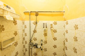 Un baño con paredes amarillas, ducha y un inodoro con un estampado de flores.