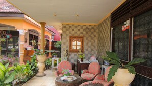 A well-maintained indoor garden area with potted plants, comfortable seating, and decorative elements. - OYO 1721 A. Yani 95 Residence (Banyuwangi)
