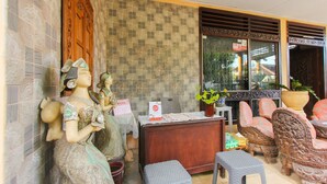 A room with a reception desk, a statue, a potted plant, and traditional chairs. - OYO 1721 A. Yani 95 Residence (Banyuwangi)