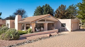 Ein modernes Haus mit überdachter Terrasse, Garage und begrüntem Auffahrt.