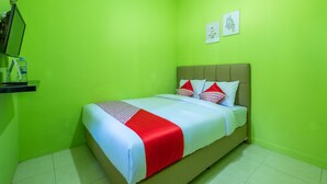 A room with a bed, green walls, and two framed pictures on the wall. - OYO 1399 Cemara Residence Syariah (West Cirebon)
