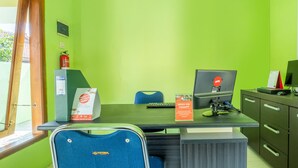 A room with a green wall, a wooden door, a desk with a computer, a chair, and a bookshelf. - OYO 1399 Cemara Residence Syariah (West Cirebon)