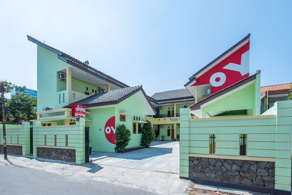 A modern two-story building with a green facade and a prominent red and white sign.