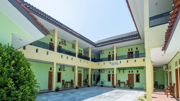 A multi-level courtyard with balconies, potted plants, and a central staircase. - OYO 1399 Cemara Residence Syariah (West Cirebon)
