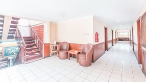 Vestíbulo de hotel con escalera, zona de estar y extintor.