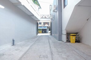 A narrow alleyway with a concrete floor, a yellow trash bin, and a potted plant. - Oyo 1454 111 Residence (Batu)