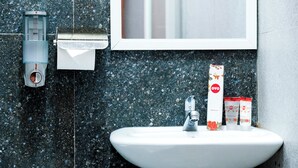 A bathroom with a sink, a mirror, a toilet paper dispenser, and a dental kit. - Oyo 1454 111 Residence (Batu)