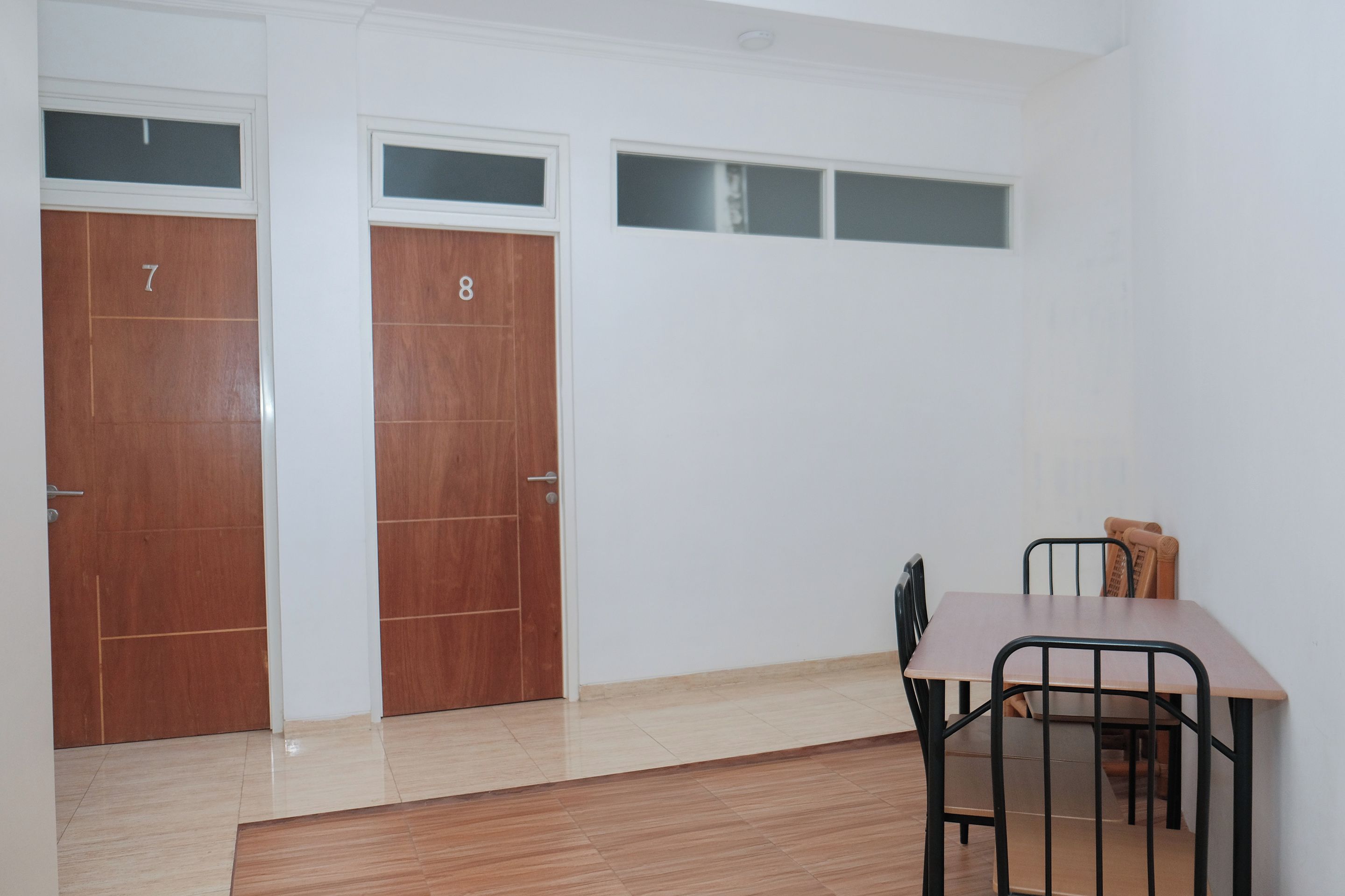 A room with two wooden doors, numbered 7 and 8, a table with chairs, and a small window.