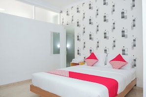 Ett hotellrum med en säng, en spegel och en vägg med ett geometriskt mönster.