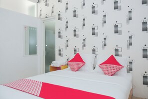 A hotel room with a bed, two pillows, a red throw, and a patterned wall. - Oyo 1454 111 Residence (Batu)