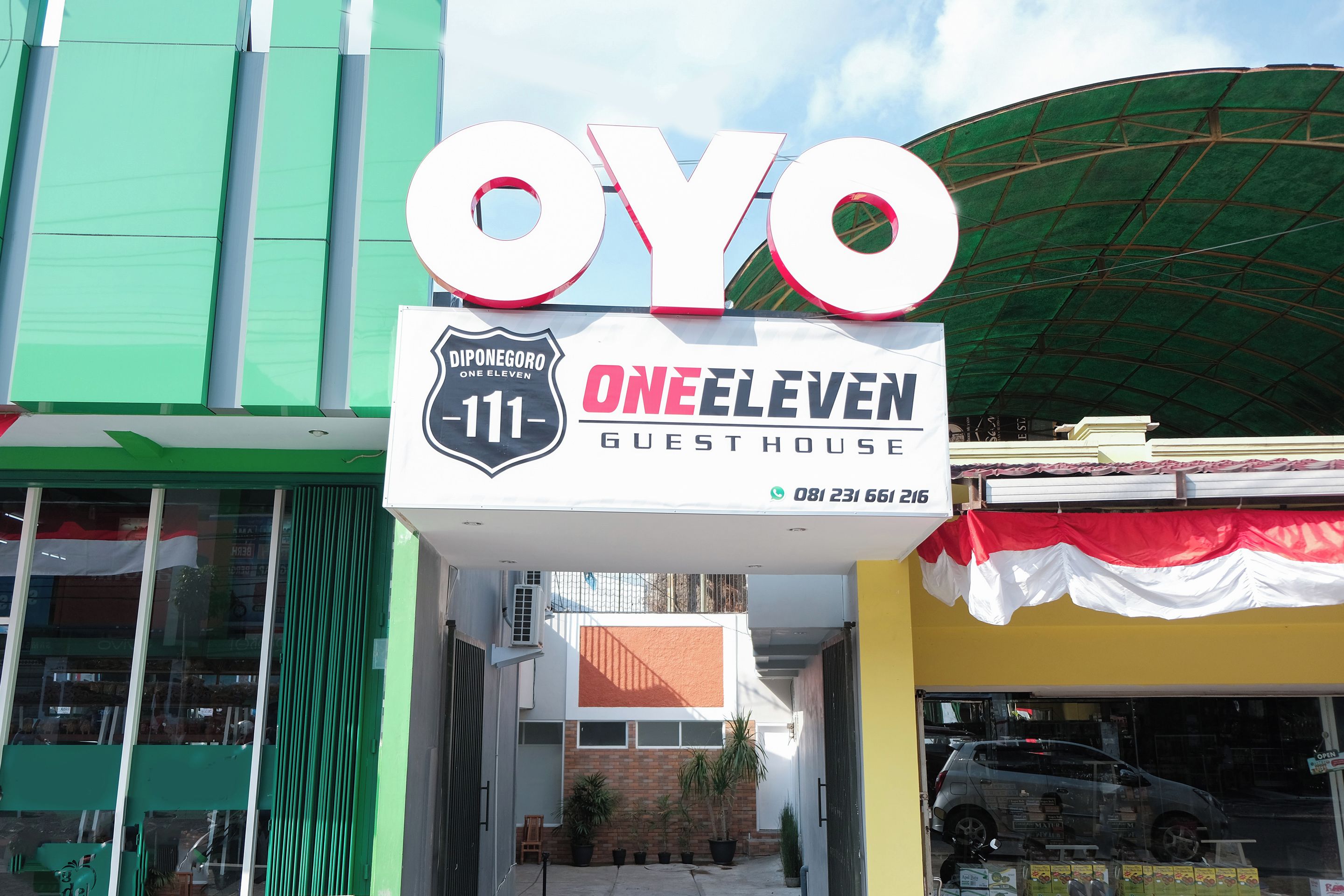 A sign for 'OYO One Eleven Guest House' with a contact number.