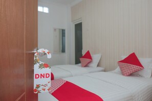 A hotel room with two beds, each with red pillows and a red blanket. A door with a sign reading 'DND' is visible. - Oyo 1454 111 Residence (Batu)