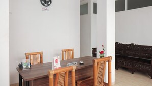A dining area with a wooden table, four chairs, a clock, and a 'No Smoking' sign. - Oyo 1454 111 Residence (Batu)