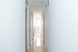 A bright, well-lit hallway with a glossy floor leading to a room with a large window. - Oyo 1454 111 Residence (Batu)