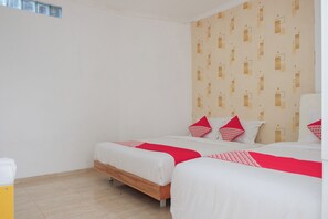 A hotel room with two beds, a wooden floor, and a patterned wall. - Oyo 1454 111 Residence (Batu)