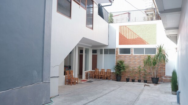 A modern two-story building with a covered patio area, outdoor seating, and potted plants. - Oyo 1454 111 Residence (Batu)