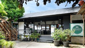 Ein Gebäude mit überdachter Eingangspartei, Blumentöpfen und einem Schild für 'YakMoer House & Bed Cafe'.