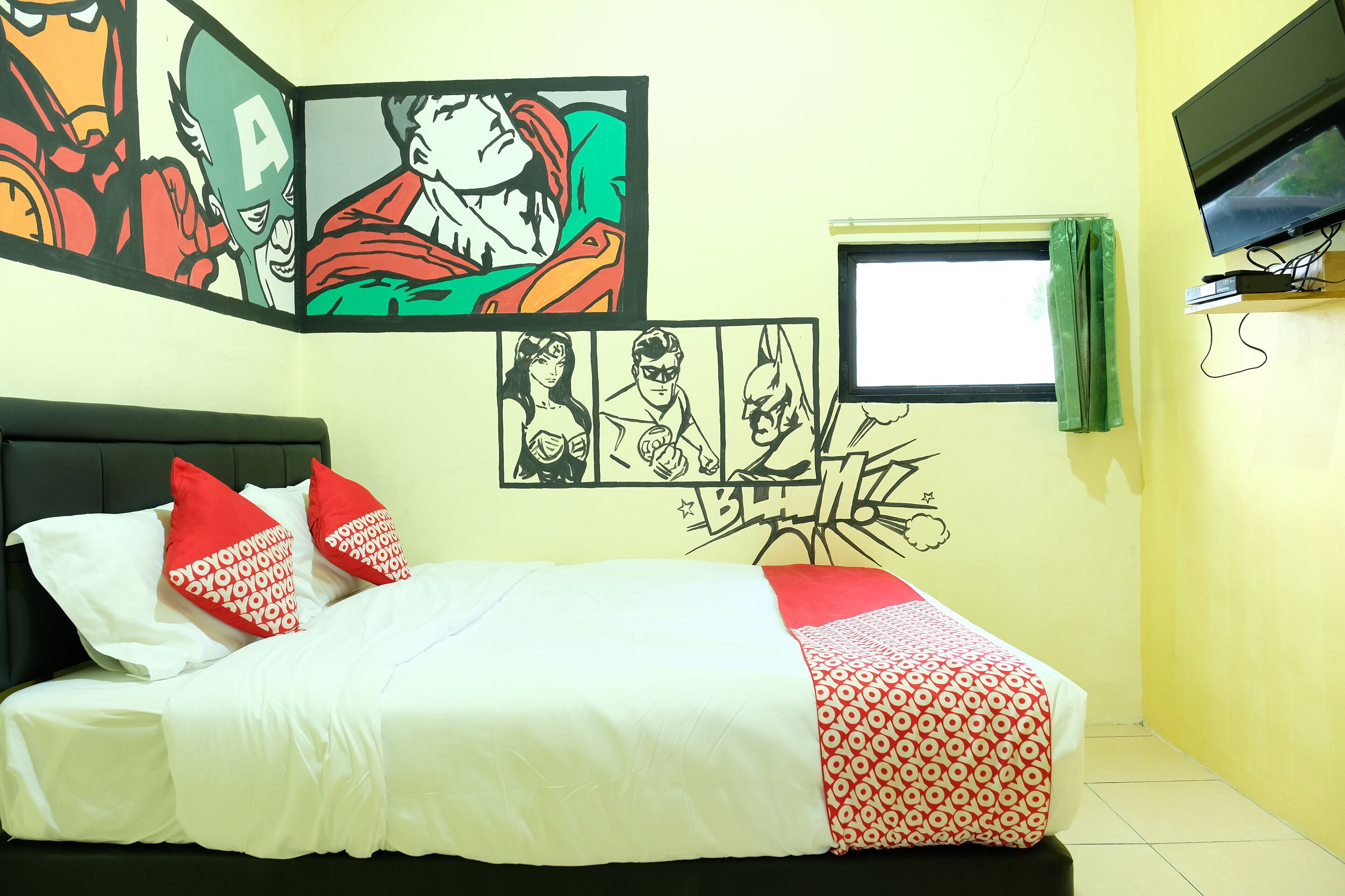 A bedroom with a bed, pillows, a TV, and comic book art on the wall.
