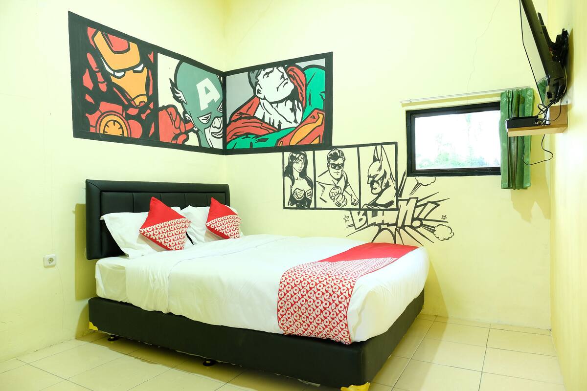 Un dormitorio con una cama, un televisor de pared y decoración con temática de superhéroes.