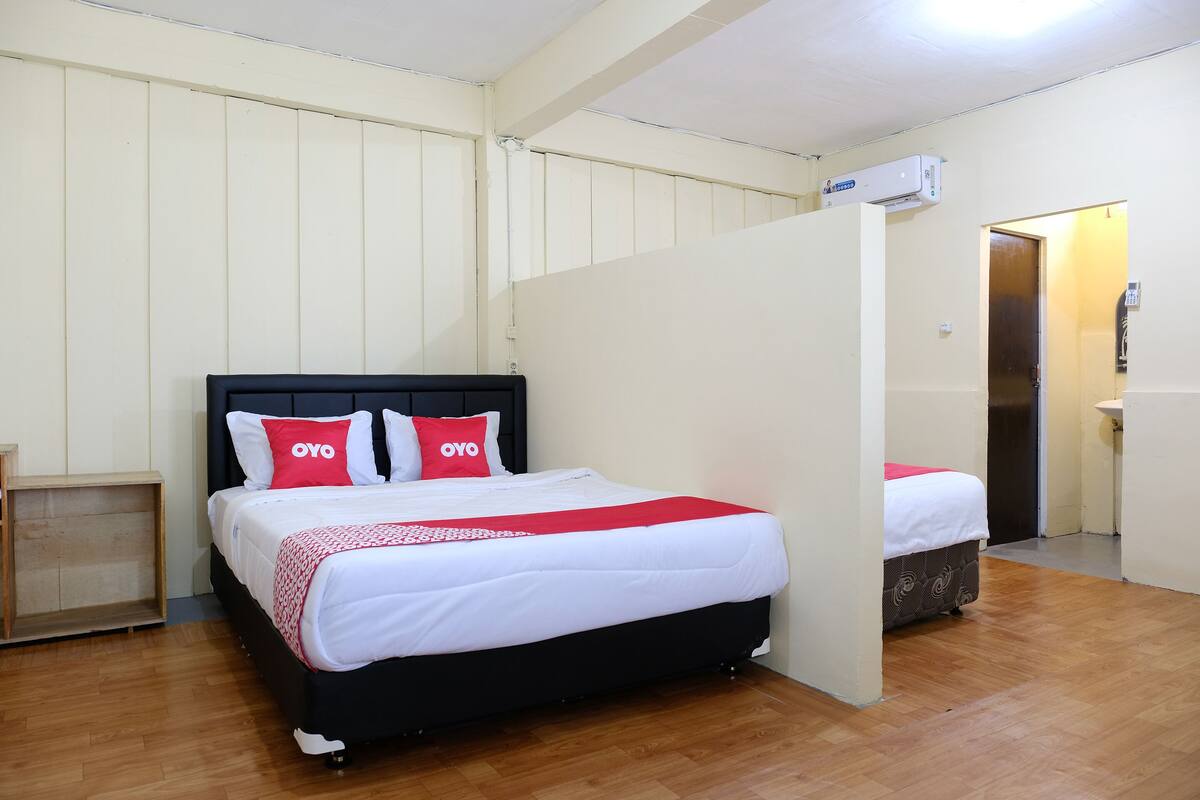 Una habitación de hotel con cama, mesita de noche, armario y baño visible a través de una puerta abierta.