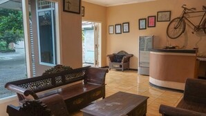 A reception area with a wooden bench, a small table, and a bicycle mounted on the wall. - Hotel O Jatimas (Merawang)