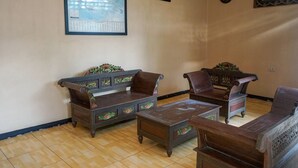 A traditional living room with wooden furniture, a map on the wall, and a clock. - Hotel O Jatimas (Merawang)