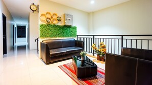 Un salon moderne avec un canapé en cuir, une table basse et un mur vert orné de motifs hexagonaux.