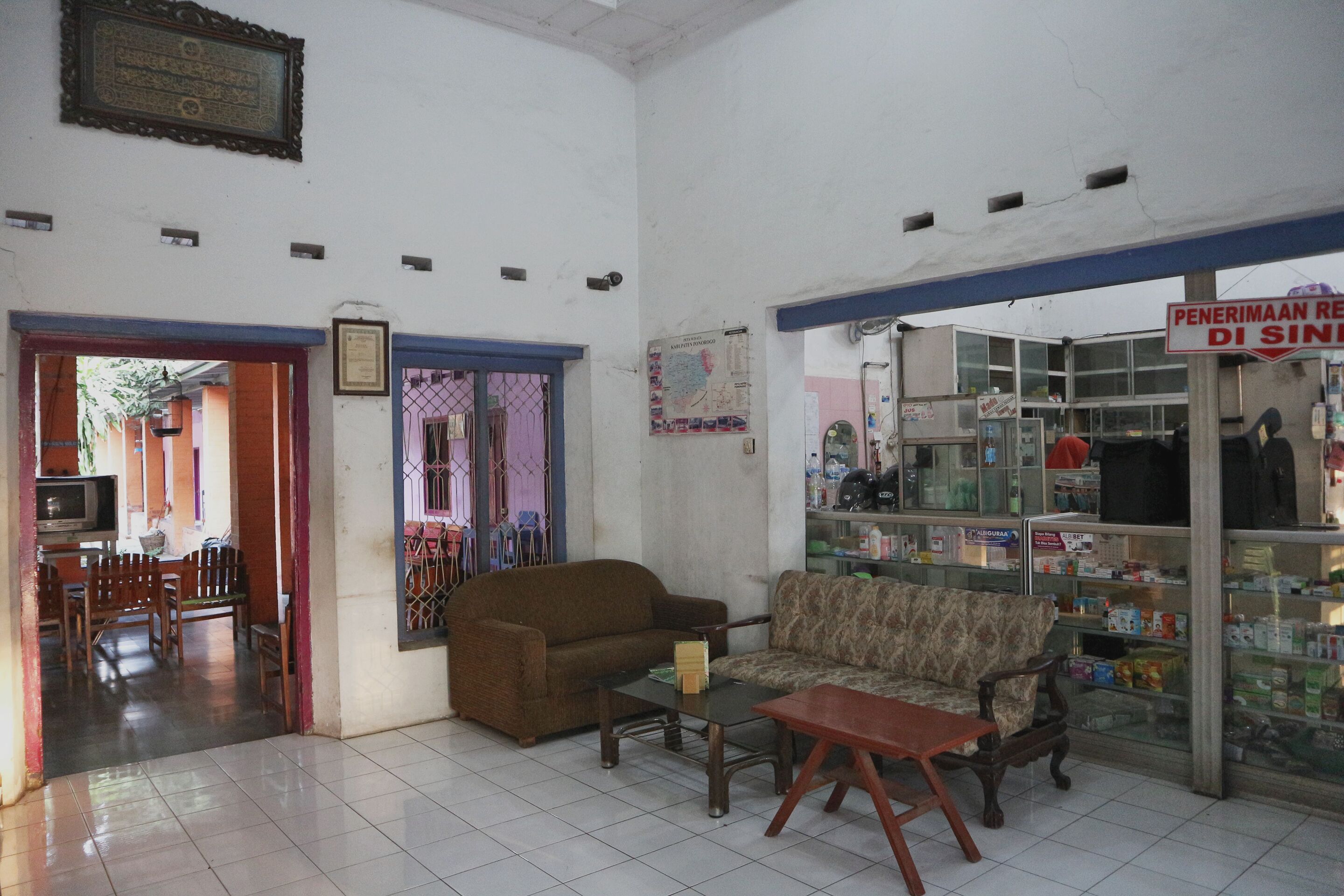 A living room with two sofas, a coffee table, and a television. There is a doorway leading to another room with a dining table and chairs.