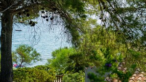A coastal garden with a pathway leading to a white building with a tiled roof. - Villa Giuliana - Rare Beachfront Villa - Direct private access to sandy beach (Torre Delle Stelle)