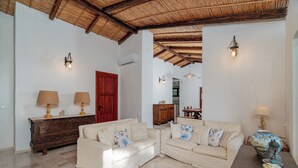 A spacious living room with two sofas, a wooden cabinet, and a red door. - Villa Giuliana - Rare Beachfront Villa - Direct private access to sandy beach (Torre Delle Stelle)