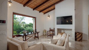 A spacious living area with a large window, a fireplace, and a television mounted on the wall. - Villa Giuliana - Rare Beachfront Villa - Direct private access to sandy beach (Torre Delle Stelle)