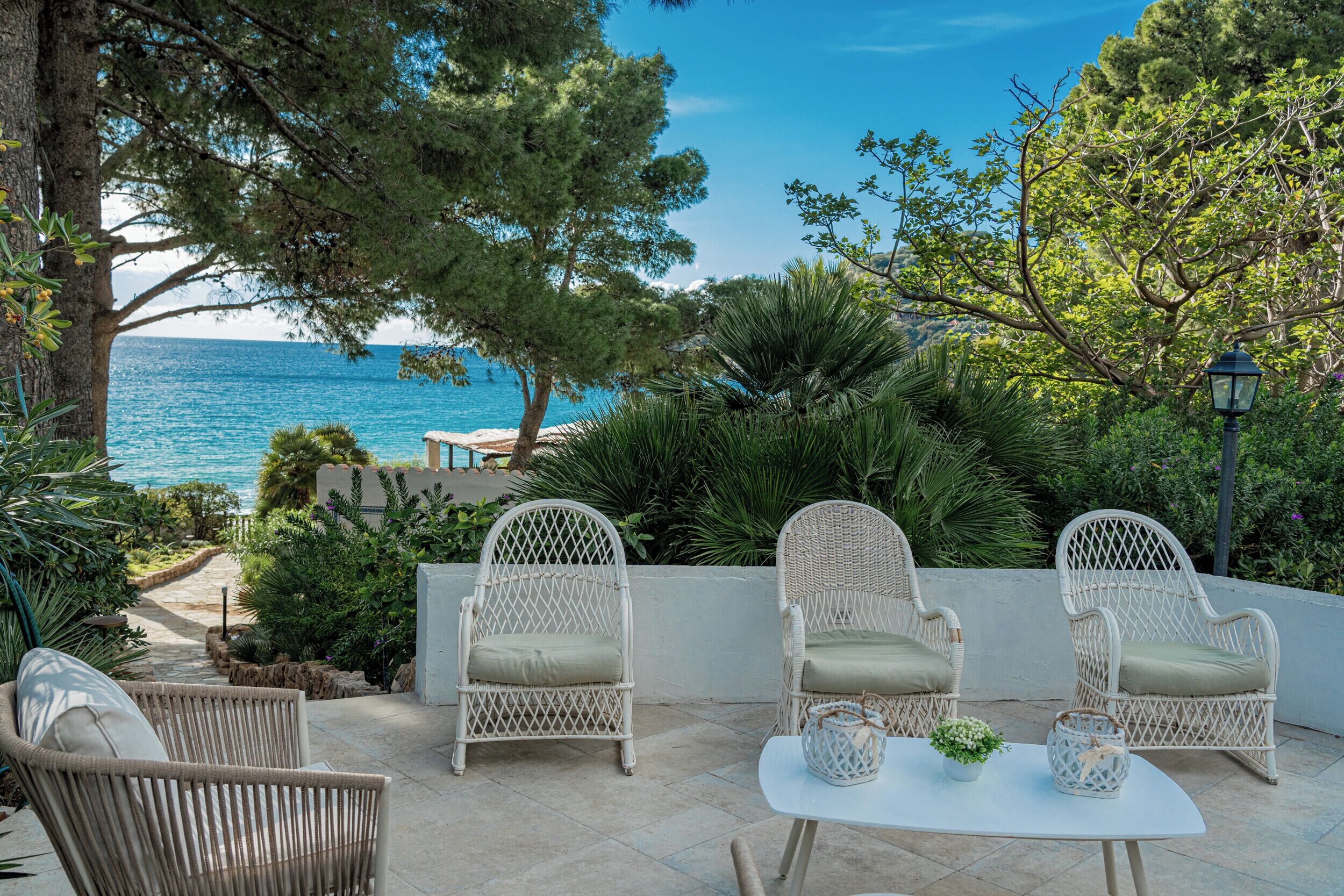 An outdoor seating area with wicker chairs and a table, overlooking a body of water.