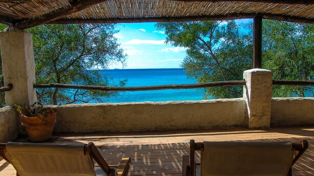 A covered outdoor seating area with a view of the sea and trees. - Villa Giuliana - Rare Beachfront Villa - Direct private access to sandy beach (Torre Delle Stelle)