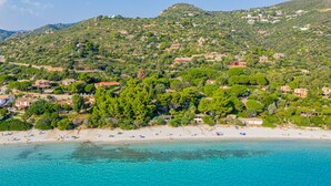 A coastal area with a beach, clear turquoise waters, and a hillside with scattered buildings. - Villa Giuliana - Rare Beachfront Villa - Direct private access to sandy beach (Torre Delle Stelle)