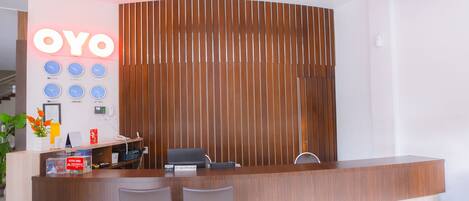 A reception desk with a wooden finish, a clock display, and a nameplate for the receptionist.