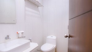 Een badkamer met een wit wastafelmeubel, toilet en douche.