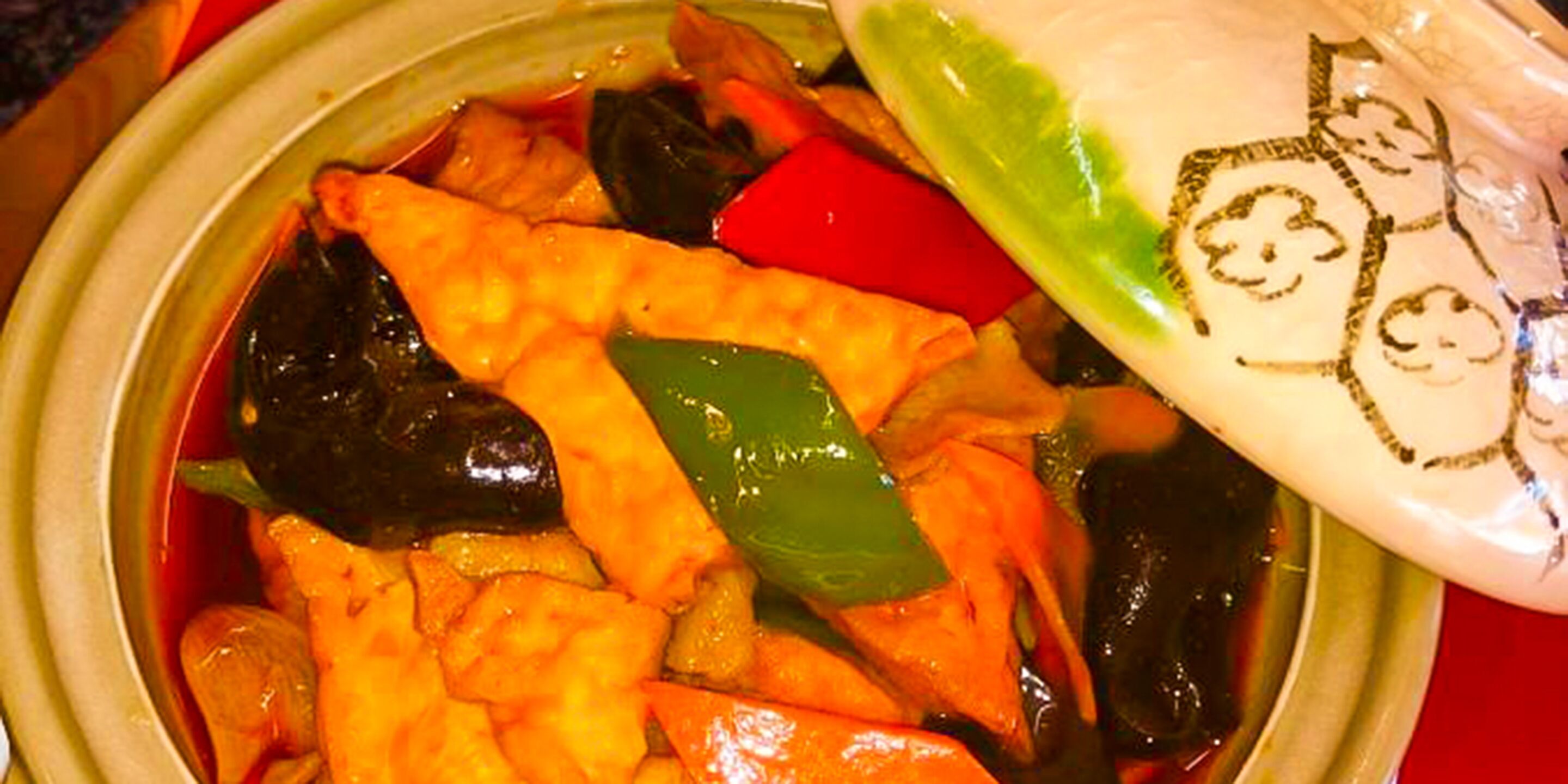 A bowl of soup with vegetables and a spoon.