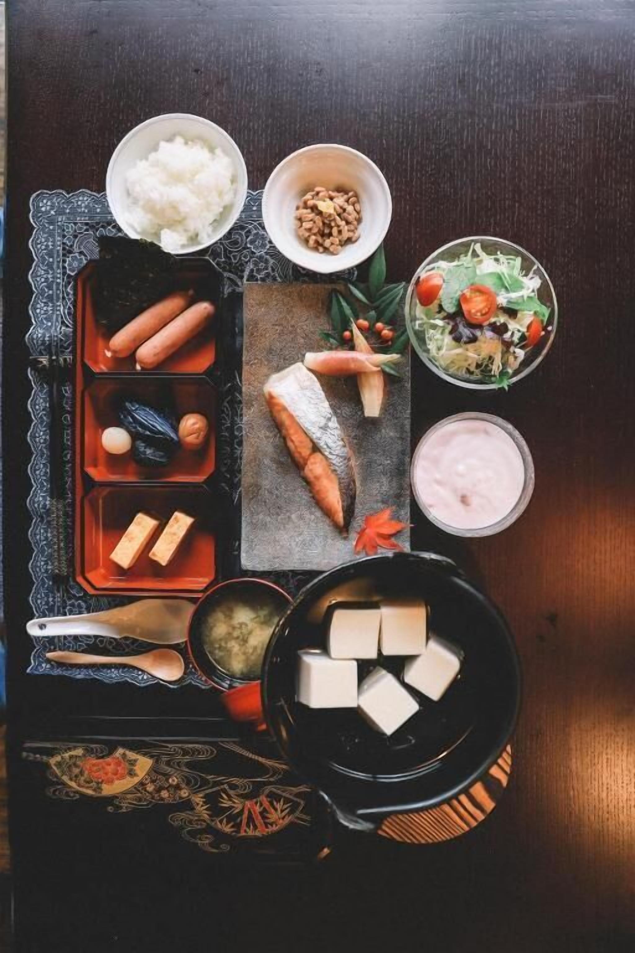 Uma refeição montada com diversos pratos, incluindo arroz, peixe, legumes e uma tigela de sopa.