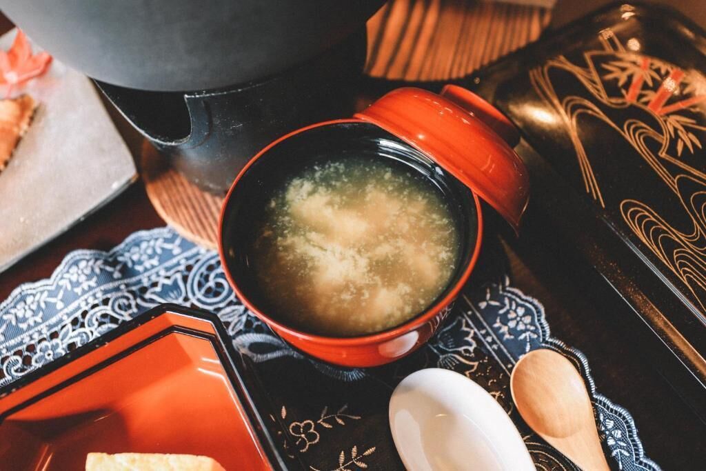 Um conjunto de chá tradicional japonês, com uma tigela de chá preta e vermelha, um bule preto e um tabuleiro estampado.