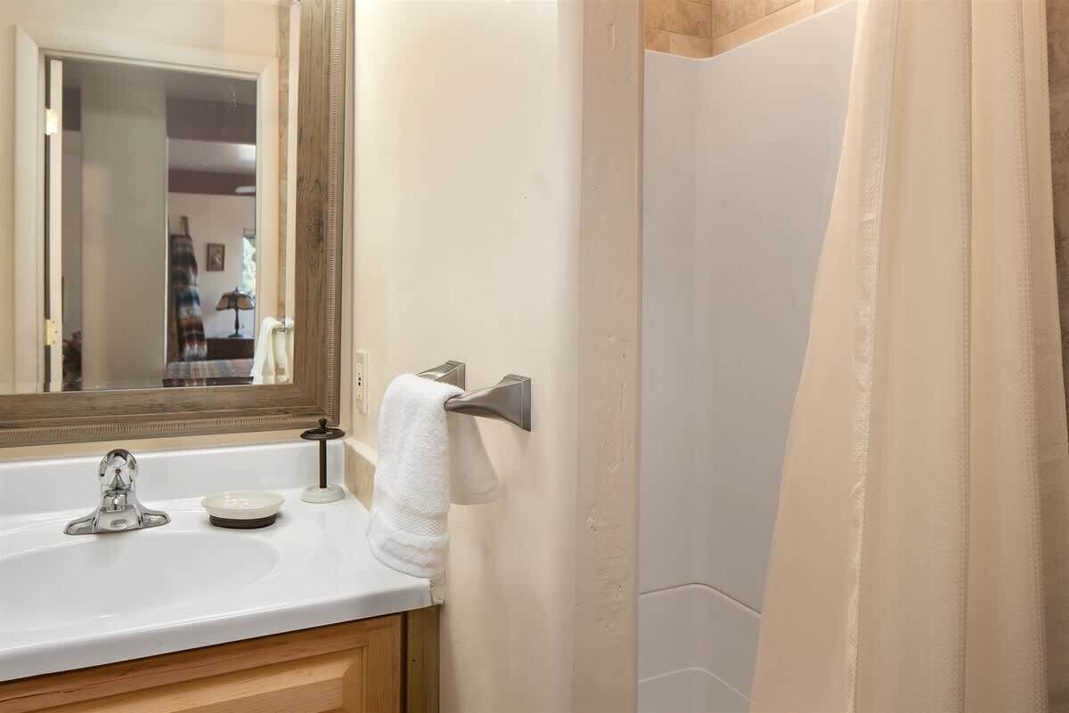 A bathroom with a sink, mirror, towel rack, and shower curtain.
