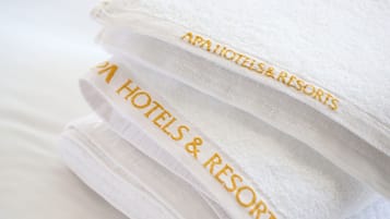 Uma pilha de toalhas brancas com bordado contendo o texto "AAA HOTELS & RESORTS".