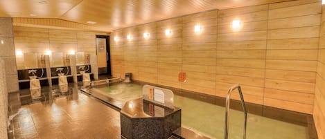 Eine öffentliche Sauna mit mehreren Bänken und einem zentralen Whirlpoolbereich.