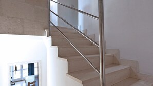 Un escalier avec une rampe métallique menant au deuxième étage.