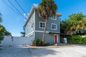 A two-story house with a red door, a white fence, and a palm tree in front. - Siesta Key Beachfront Escape 3 BR Condo (Siesta Key)